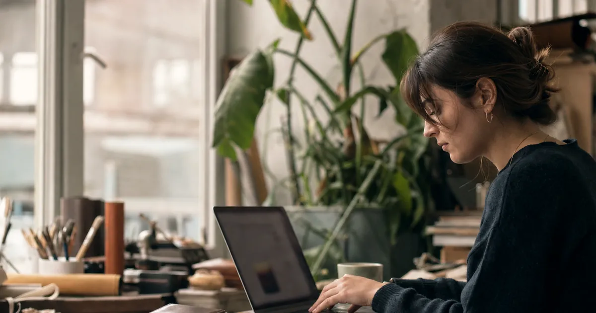 Masada ürünü yanına koyup laptopta çalışan bir kadın