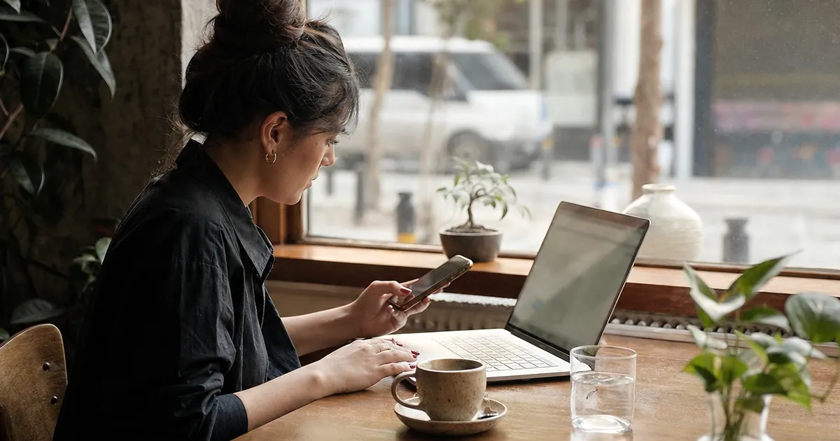 Kafede laptop başında çalışan bir kadın; masada kahve ve telefon