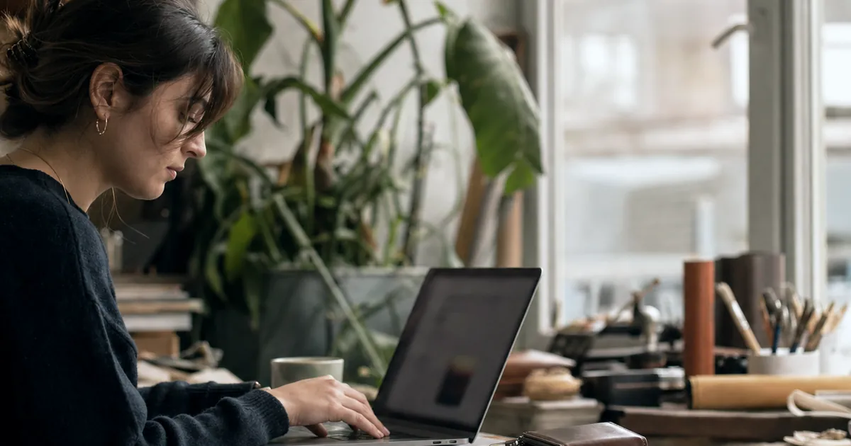 Masada ürünü yanına koyup laptopta çalışan bir kadın